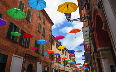 bunte Sonnenschirme hängen über der Straße von Ferrara